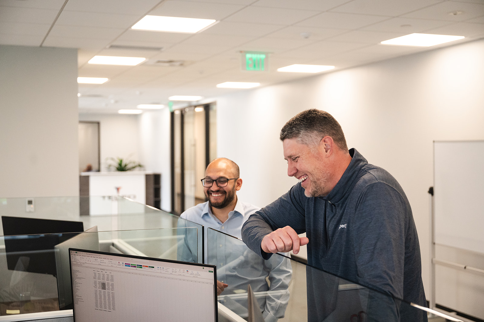 Two TELEO colleagues laughing at a workstation